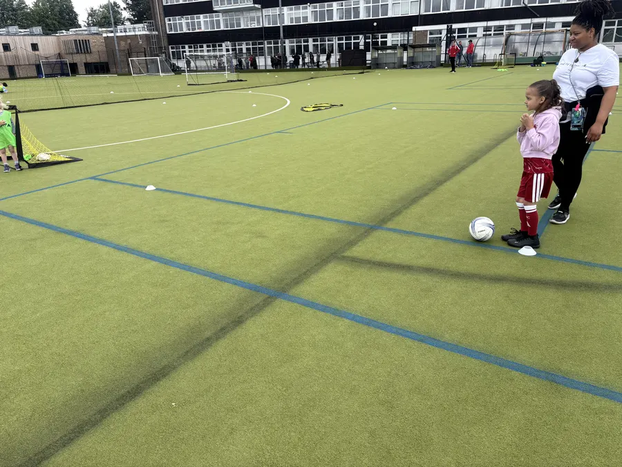 A young player on the ball with a coach watching